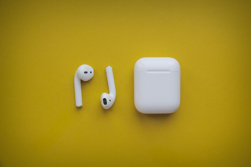 air pods and air pod case laid flat on yellow background