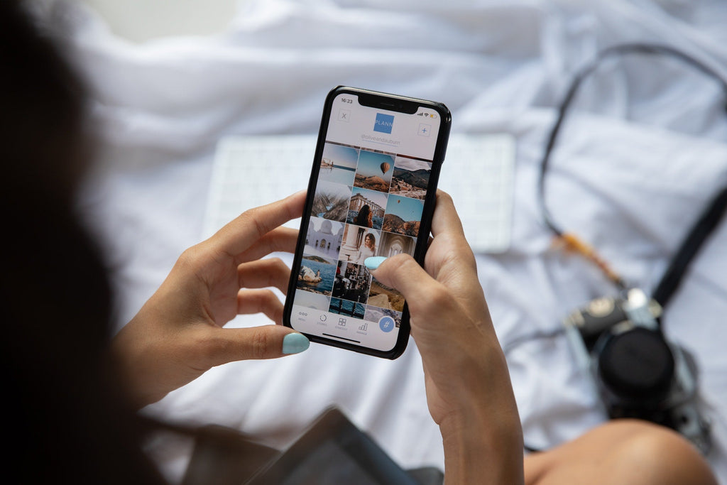 Two hands using a smartphone which in focus shows social media photographs