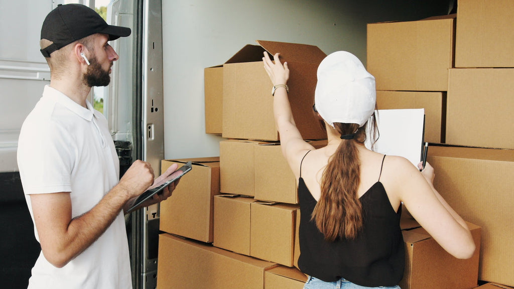 A man and a woman packing cardboard boxes in a room