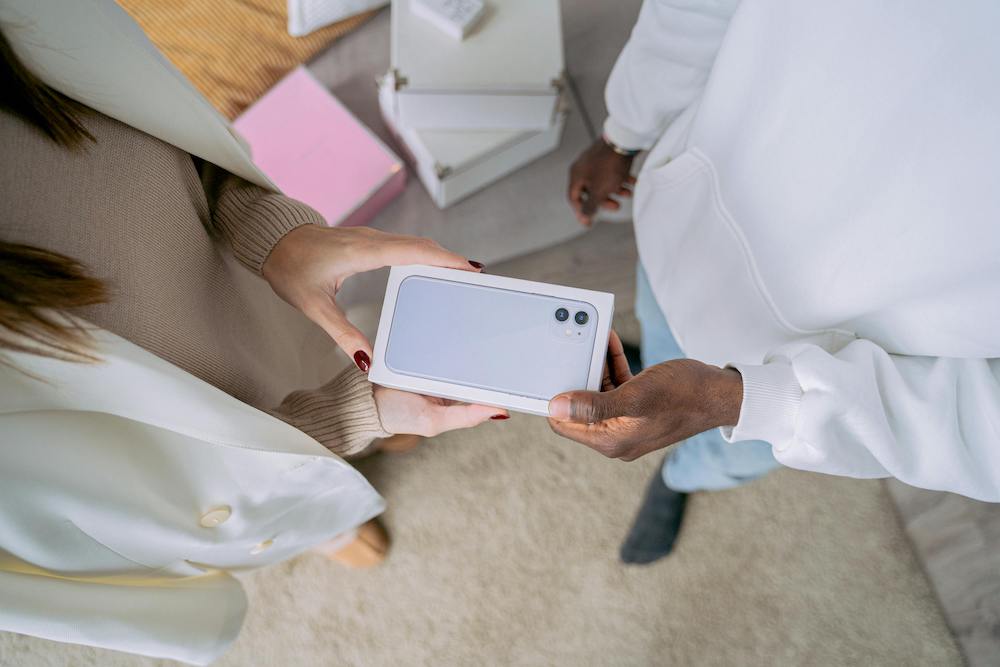 One person gifting an iPhone to another