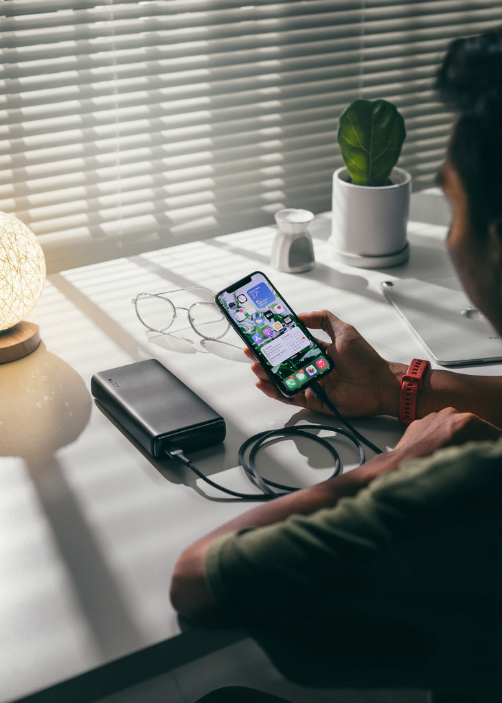person sat charging their smartphone using a portable charging block